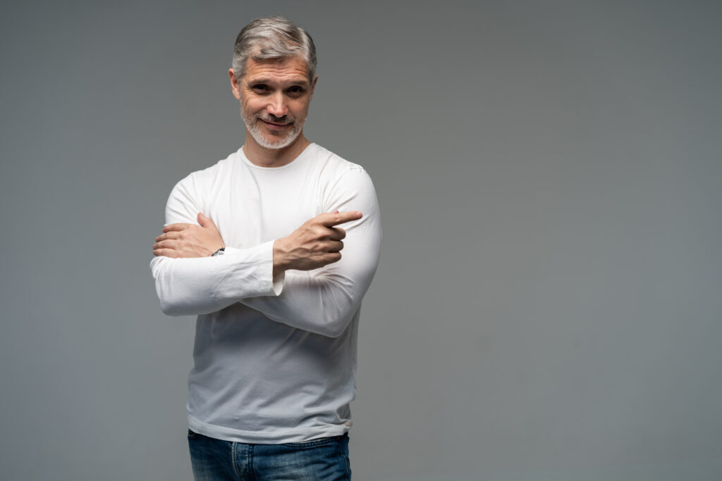 Handsome man crossing arms on grey background