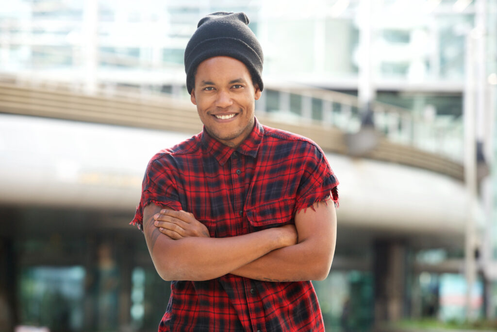 Portrait of fashionable african american man smiling outside in city with beanie